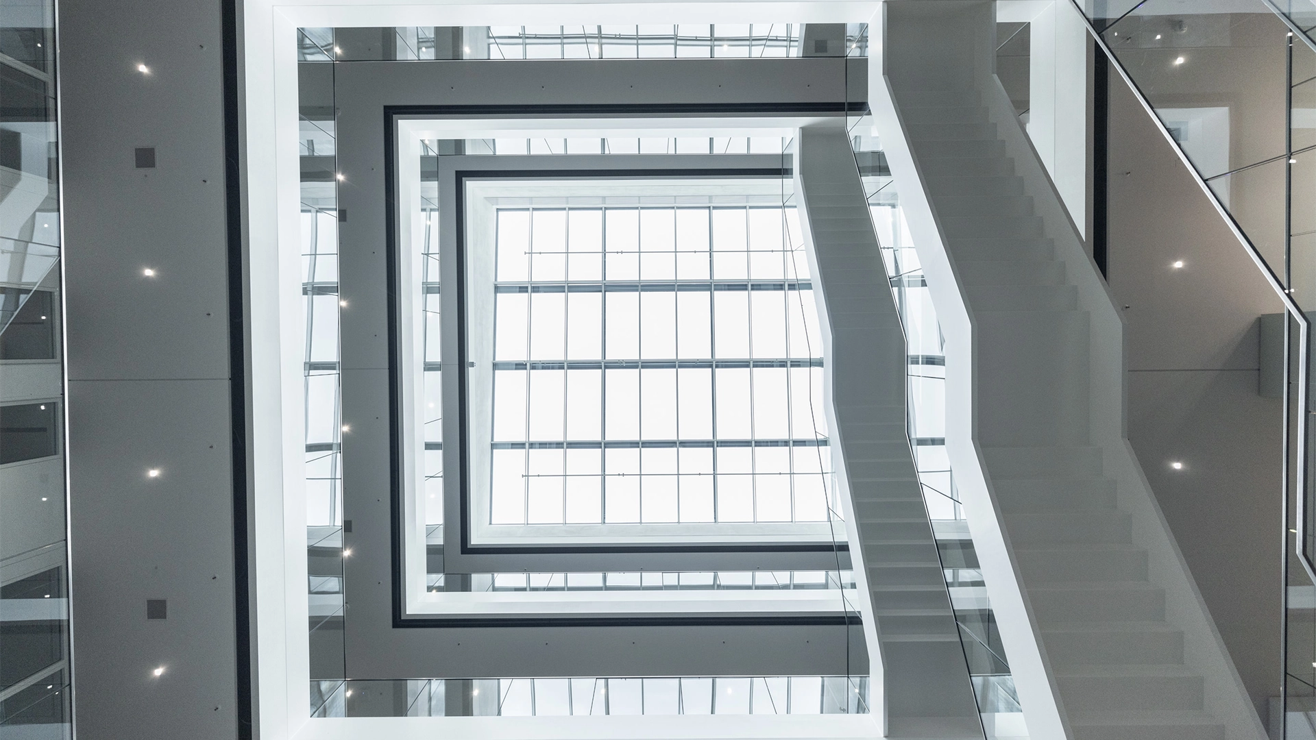 View into the atrium with a glass ceiling, white staircases, and symmetrical architecture. (photo)