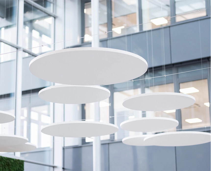 Several white, round ceiling panels hang in a bright room with high ceilings and an open-plan layout.